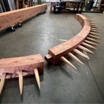 The spikey top of an unfinished wooden Sutter's Fort Gate rests on a workroom floor