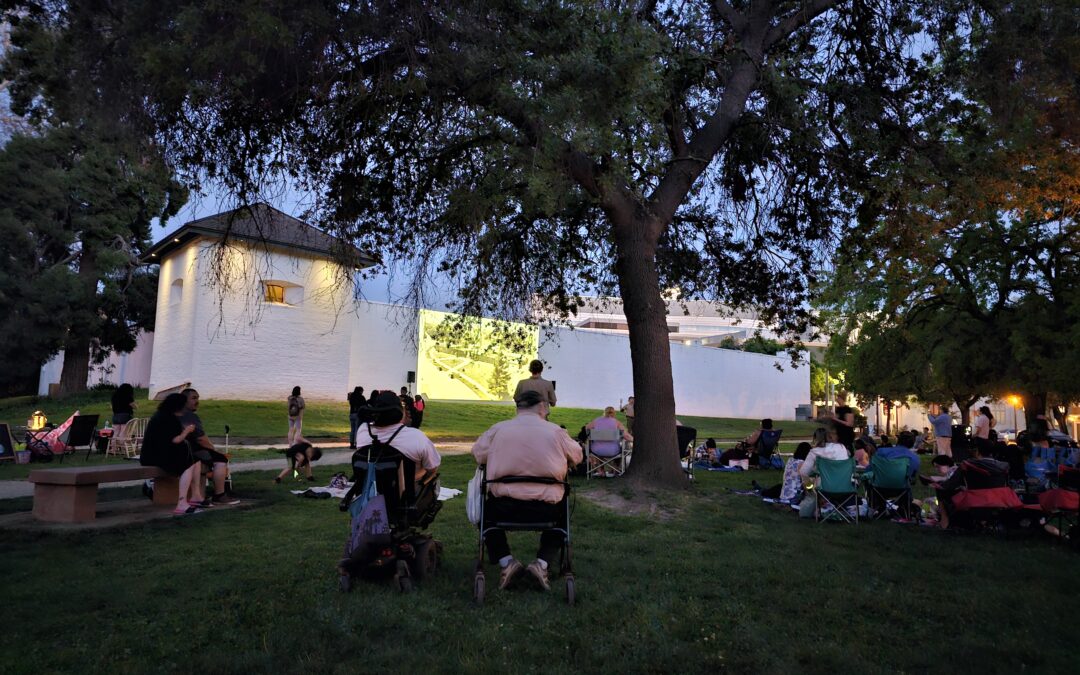 people watch from the lawn as a movie is projected onto the walls of Sutter's Fort.