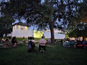 people watch from the lawn as a movie is projected onto the walls of Sutter's Fort.