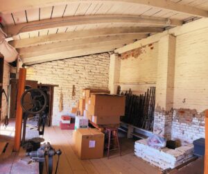 adobe brick walls, wood plank ceiling with boxes stacked up against wall. 