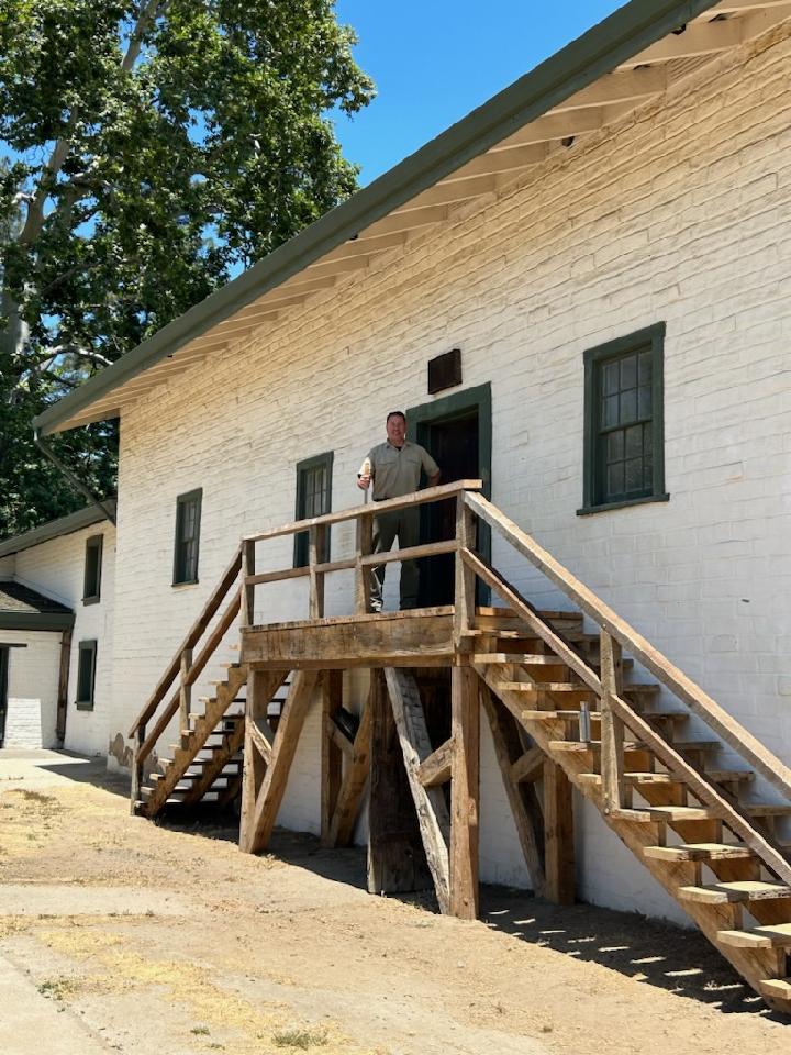 Tim White stands at the top of wooden staircase at the Central Building in Sutter's Fort.