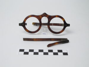 Pair of old eyeglasses with one part of the frame laying in front.