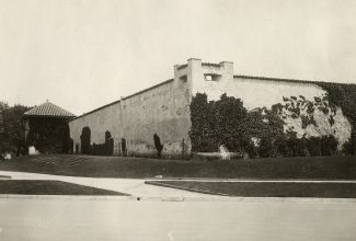 black and white image of white brick fort walls partially covered by vines.